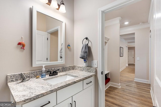 bathroom with ornamental molding, wood finished floors, vanity, and baseboards