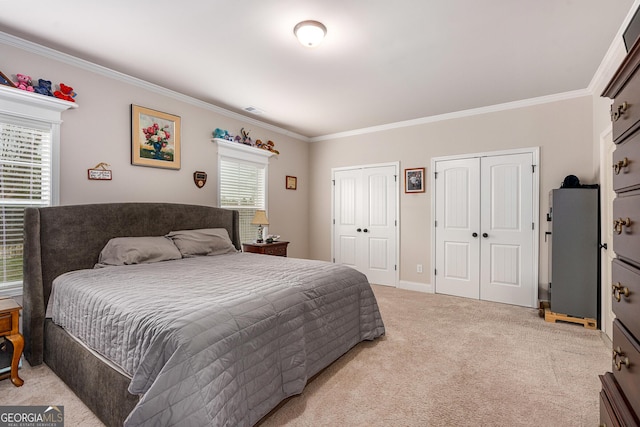 bedroom with light carpet, visible vents, baseboards, two closets, and crown molding