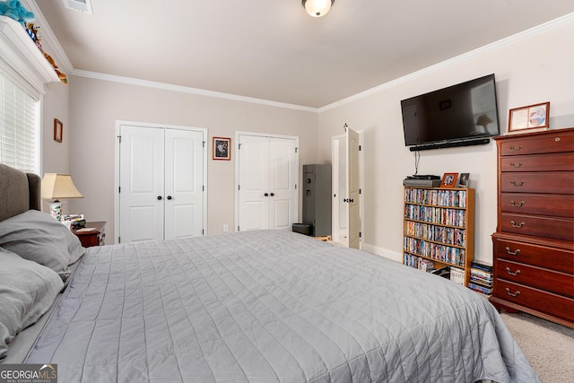 carpeted bedroom with ornamental molding and two closets