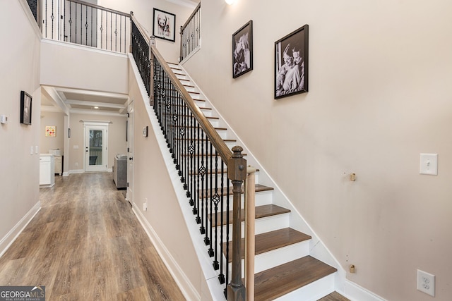 stairs featuring a high ceiling, wood finished floors, and baseboards