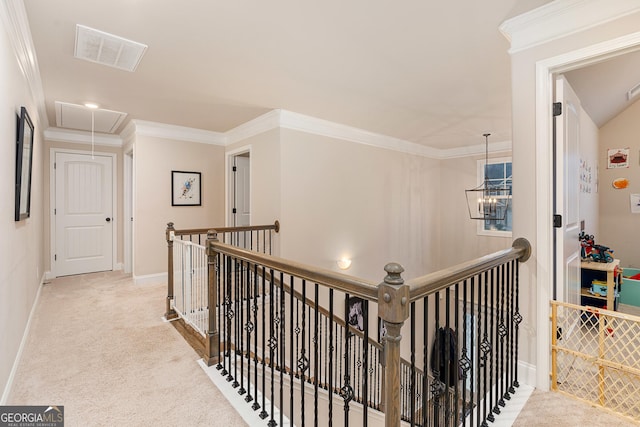 hallway featuring attic access, visible vents, ornamental molding, carpet, and an upstairs landing