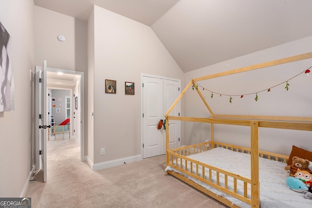 carpeted bedroom with baseboards, high vaulted ceiling, and a closet