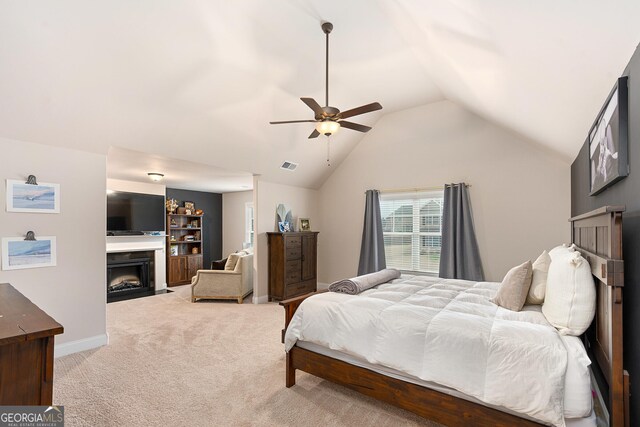 bedroom featuring visible vents, baseboards, lofted ceiling, a fireplace with flush hearth, and carpet