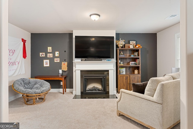 carpeted living room featuring a fireplace with flush hearth, visible vents, and baseboards