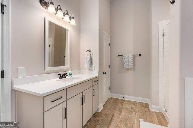 full bath with a shower, wood finished floors, vanity, and baseboards