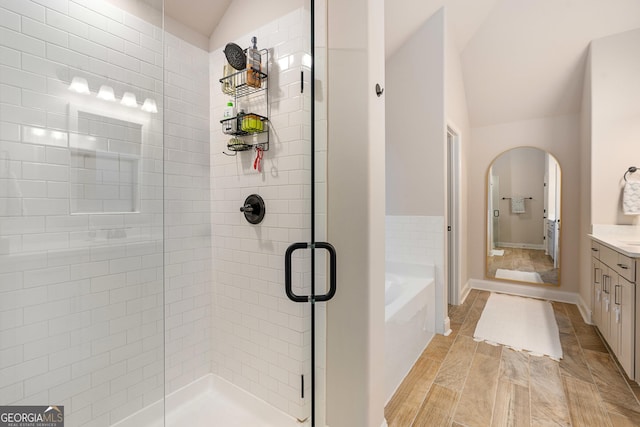 bathroom with a garden tub, a shower stall, vaulted ceiling, and vanity