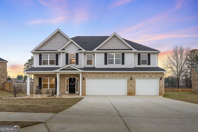 view of front of house with a garage, driveway, fence, and brick siding