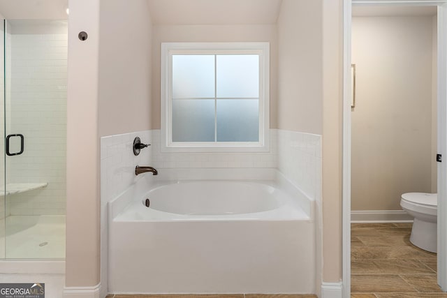 bathroom with toilet, a stall shower, baseboards, and a garden tub