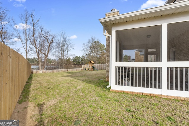 view of yard featuring a sunroom, a playground, and a fenced backyard