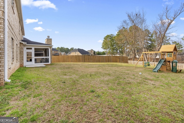 view of yard featuring a sunroom, a playground, and fence