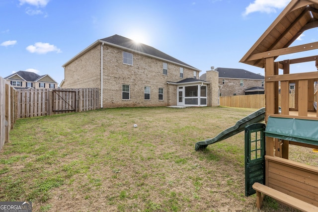 rear view of property with a yard, a fenced backyard, and a sunroom