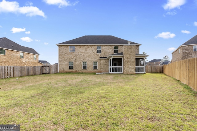 rear view of house featuring brick siding, a lawn, and a fenced backyard