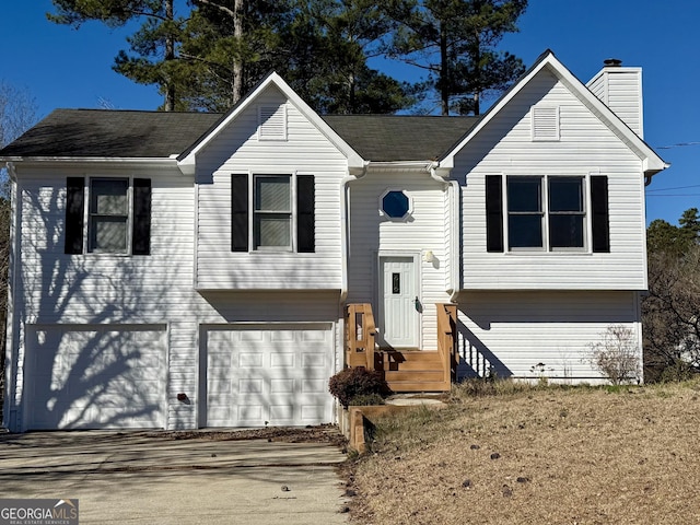 raised ranch with a garage, driveway, and a chimney