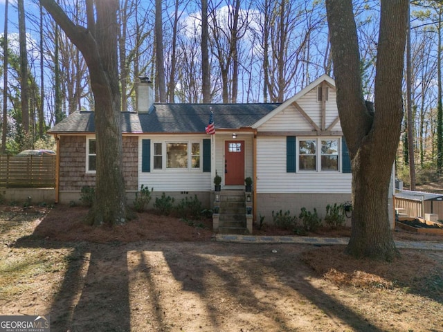 view of front of house with a shingled roof, crawl space, a chimney, and fence