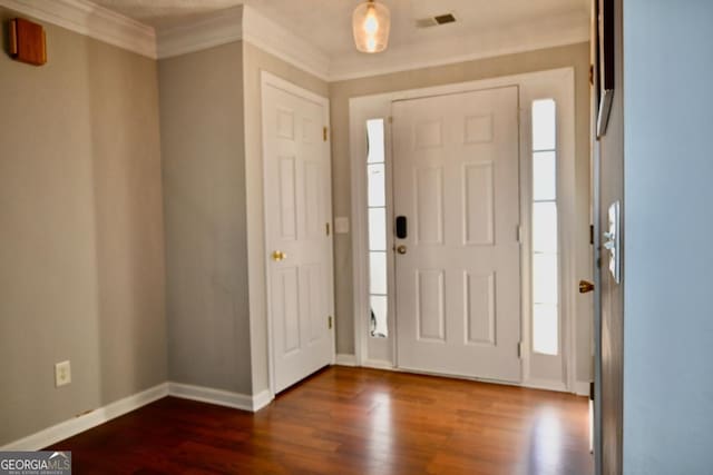 foyer entrance with crown molding, visible vents, dark wood finished floors, and baseboards