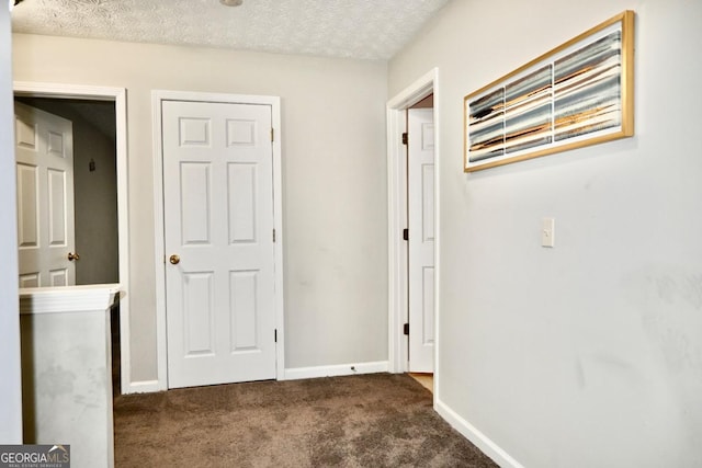 hall with carpet, a textured ceiling, and baseboards