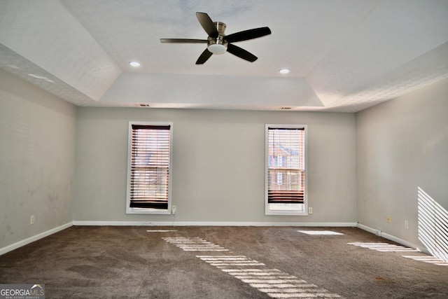 empty room with a tray ceiling, carpet, and baseboards