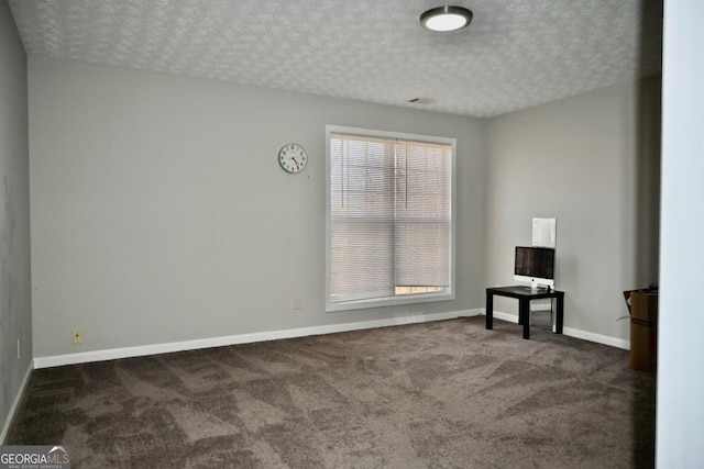 unfurnished room with a textured ceiling, carpet, and baseboards