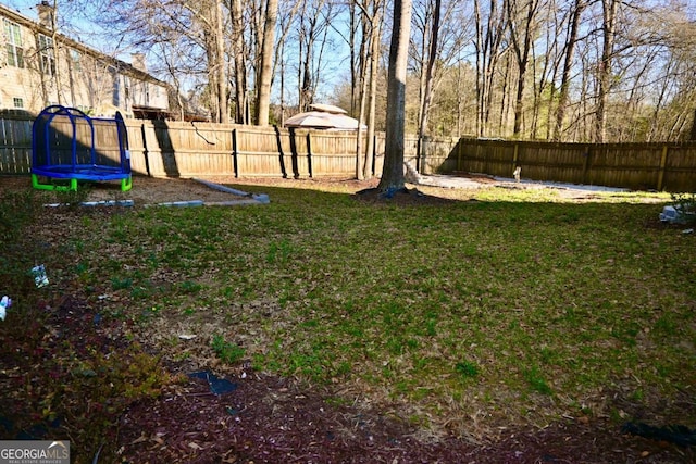 view of yard featuring a trampoline and a fenced backyard