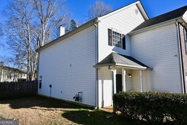 back of house with a chimney and fence