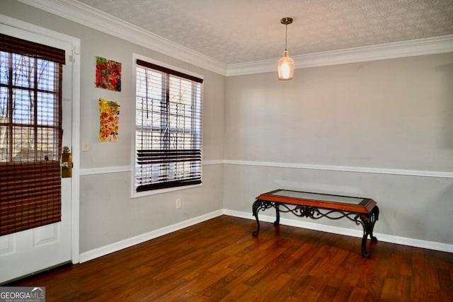 foyer with a textured ceiling, ornamental molding, wood finished floors, and baseboards