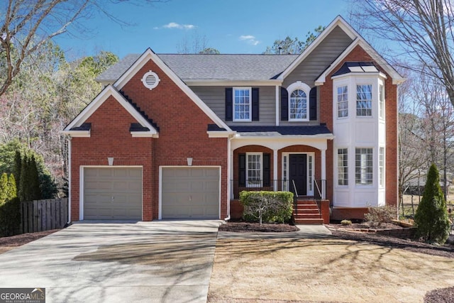 traditional-style home with a garage, driveway, brick siding, and fence