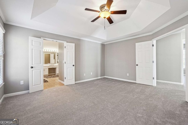 unfurnished bedroom featuring carpet flooring, a raised ceiling, and baseboards