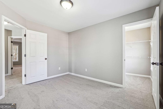 unfurnished bedroom featuring carpet, baseboards, a walk in closet, and a closet