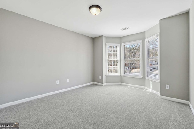 carpeted empty room featuring visible vents and baseboards