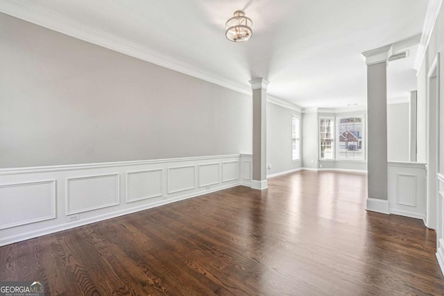 spare room with visible vents, wood finished floors, decorative columns, and crown molding