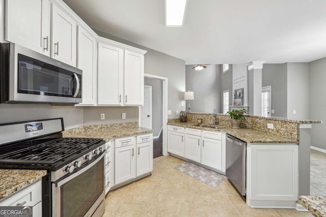 kitchen featuring stainless steel appliances, white cabinetry, a sink, and a peninsula