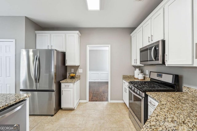 kitchen with stainless steel appliances, white cabinets, and light stone counters