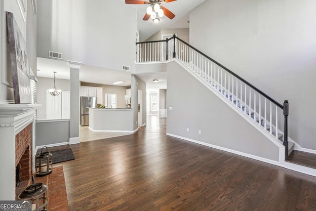 unfurnished living room featuring visible vents, stairway, baseboards, and wood finished floors