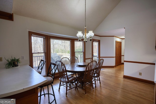 dining area with lofted ceiling, a textured ceiling, a chandelier, light wood-style flooring, and baseboards