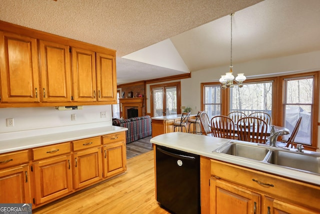 kitchen featuring light wood finished floors, black dishwasher, lofted ceiling, brown cabinets, and a sink