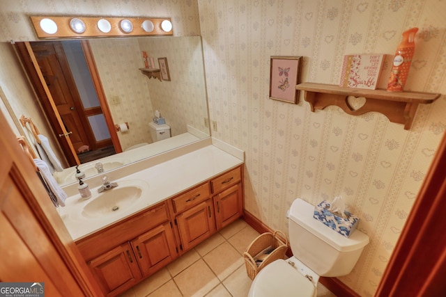 bathroom with tile patterned flooring, toilet, vanity, baseboards, and wallpapered walls