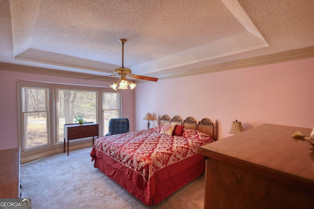 bedroom with light carpet, a tray ceiling, and a textured ceiling