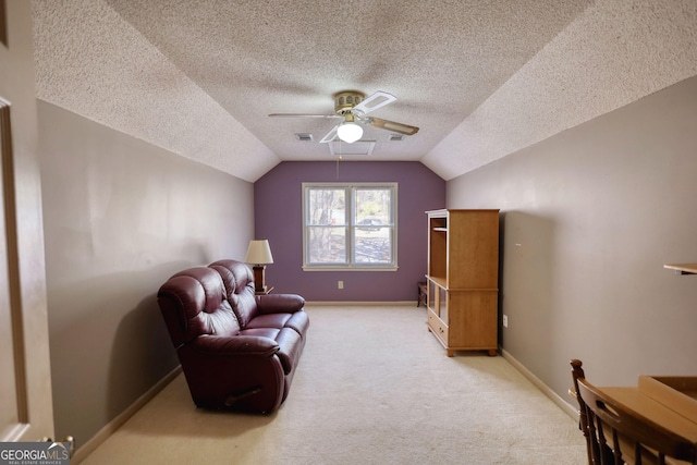 living area featuring baseboards, visible vents, light colored carpet, ceiling fan, and vaulted ceiling