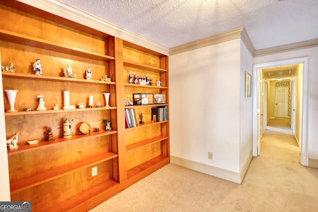 corridor with light carpet, crown molding, a textured ceiling, and baseboards