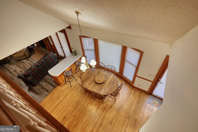 dining room featuring a textured ceiling, baseboards, and wood finished floors