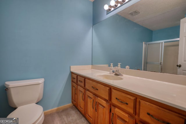 full bathroom featuring toilet, visible vents, vanity, baseboards, and a shower stall