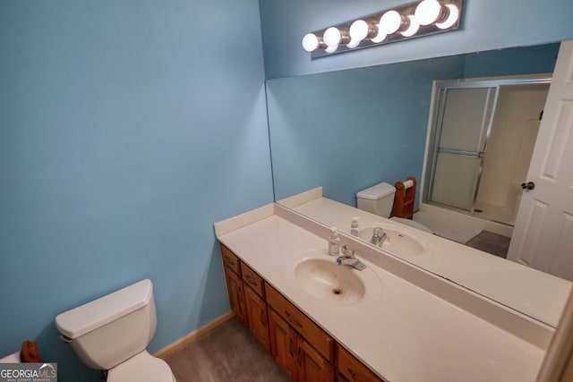 bathroom featuring a stall shower, baseboards, vanity, and toilet