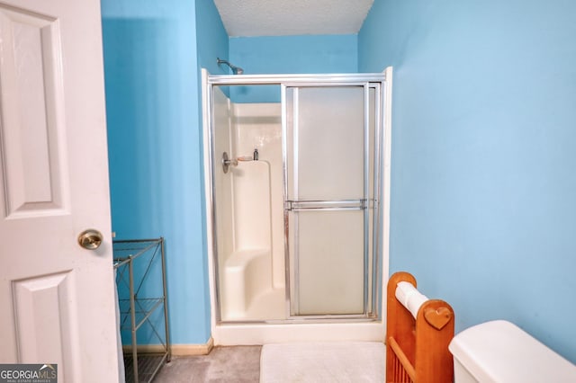 bathroom featuring a textured ceiling, a shower stall, toilet, and baseboards