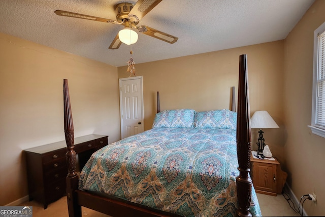 bedroom featuring a textured ceiling, baseboards, a ceiling fan, and light colored carpet