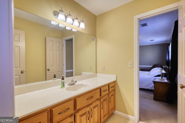 ensuite bathroom with connected bathroom, vanity, visible vents, and baseboards