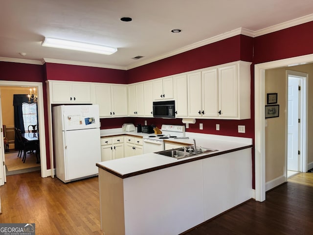 kitchen featuring a peninsula, white appliances, white cabinets, and wood finished floors