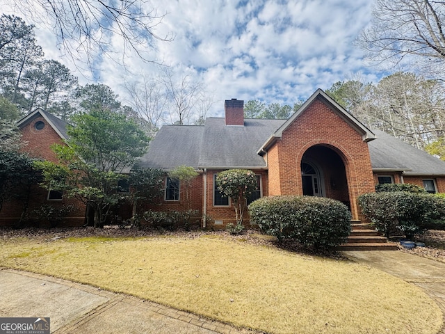 view of front of property with brick siding, roof with shingles, a chimney, crawl space, and a front lawn