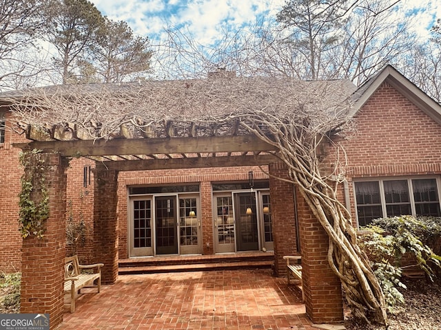 back of property with entry steps, a patio area, brick siding, and a pergola