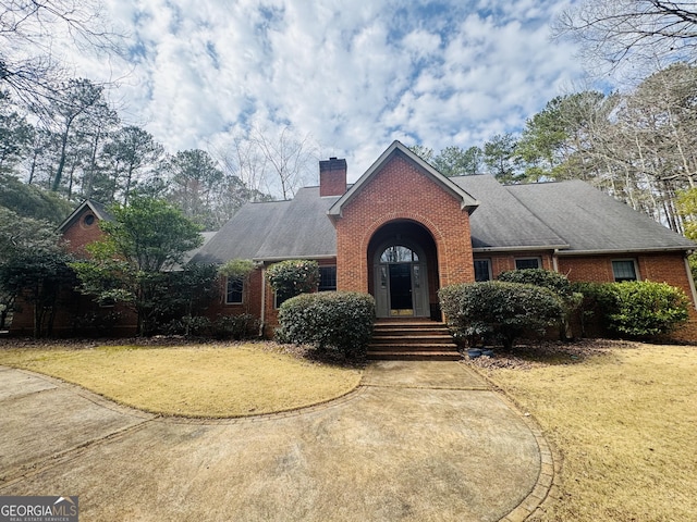 view of front of property with a chimney, a front lawn, and brick siding