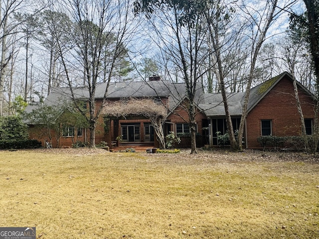 rear view of house featuring a lawn and brick siding